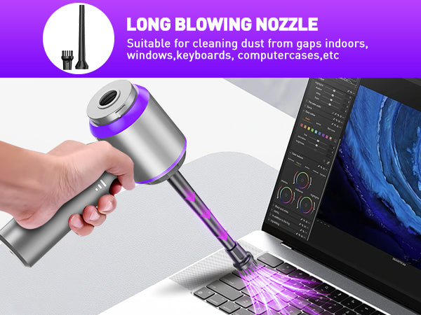 Hand holding a cleaning tool with a long blowing nozzle near a laptop.